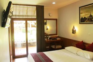 a bedroom with a bed and a desk and a window at Manohara Resort in Borobudur