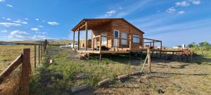 a wooden cabin in a field with a fence at Cabaña A&A in Sierra de la Ventana