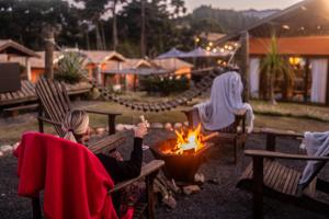 a woman sitting around a fire in a yard at Casa Brandão Pousada in Bueno Brandão