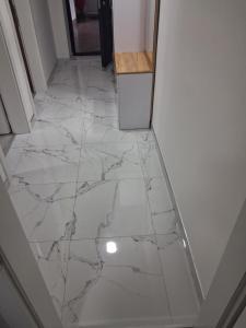 a hallway with a white marble floor with a refrigerator at Jagoda stan na dan in Prijedor