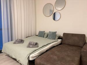 a bed with two hats on it next to a couch at Apartman SPORKA in Púchov
