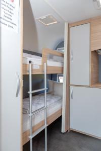 a small room with bunk beds and a refrigerator at Wohnwagenvermietung Sylt in Rantum
