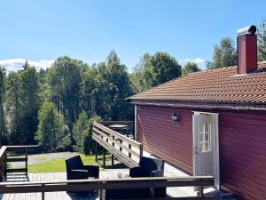 a red building with chairs on a deck at 4 person holiday home in BENGTSFORS in Bengtsfors