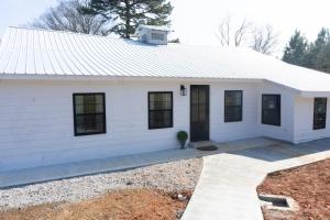a white house with black windows at Peace Barn Getaway in Carrollton
