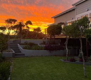 a house with a garden with a sunset in the background at Huis Seenekal in Cannon Rocks +4 photos