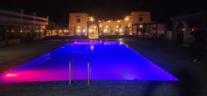 a swimming pool at night with purple lights at riad tighmart in Merzouga