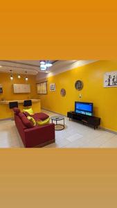 a living room with a red couch and a tv at Camara Homes1 in Saint-Louis