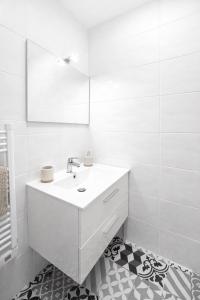 a white bathroom with a sink and a mirror at Appartement Marseille au cœur du panier in Marseille