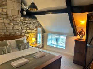 a bedroom with a large bed and a stone wall at Priory Weavers Cottage in Burford