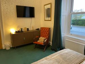 a bedroom with a bed and a chair and a tv at Rockhill Guest House in Moffat
