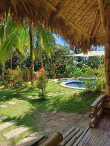 a bench under a straw umbrella next to a swimming pool at Campo De Laiya in San Juan