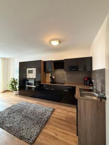 a kitchen with black cabinets and a sink and a rug at Ferienwohnungen am Luitpold in Berchtesgaden