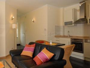 a living room with a black leather couch and a kitchen at Burg Roland Wohnung 04 in Dierhagen