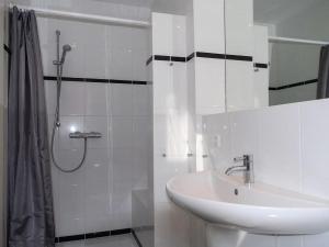a white bathroom with a sink and a shower at Burg Roland Wohnung 04 in Dierhagen