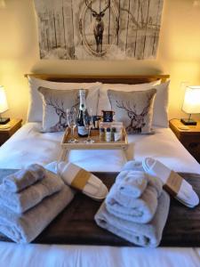 a bed with towels and glasses and a tray on it at The Old Post House in Fort William