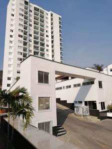 a white building with a palm tree in front of it at Espacio cómodo, piscina, jacuzzi y parqueadero in San Gil