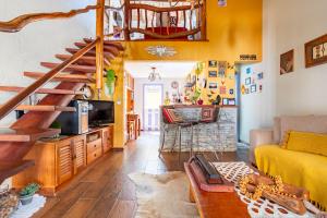 a living room with yellow walls and wooden stairs at Casinha Ipê Roxo - Condomínio Quinta do Rosário in Pirenópolis