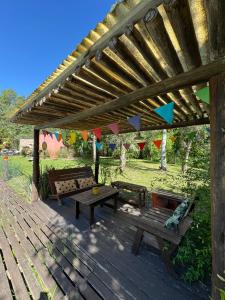 a wooden deck with benches and a wooden pergola at Galilea in San Miguel del Monte