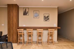a bar with four wooden stools against a wall at The Fit Stop Hostel in Hurghada