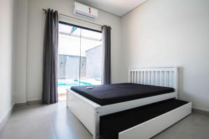 a bedroom with a bed and a large window at Casa grande alto padrão á 100 metros do mar in Guaratuba