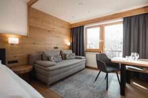 a hotel room with a couch and a desk at Jochum Hotel Garni in Fiss +44 photos