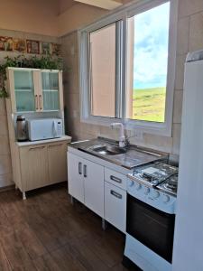 a kitchen with a sink and a stove and a window at Pousada Siriemas in Cambará