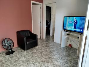 a living room with a chair and a television at Lar da Lilika Temporada in Cabo Frio +4 photos