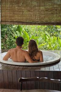 a man and woman sitting in a bath tub at Chalés Pura Vida in Itacaré