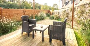 a patio with three chairs and a table on a deck at L' Antre de L' Ange in Trédarzec