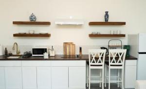 a kitchen with white cabinets and a counter with two stools at Peace Barn Getaway in Carrollton