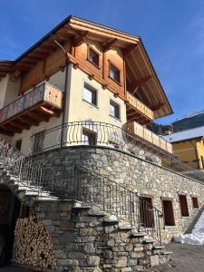 a building with a balcony on top of a stone wall at Baita Piazza in Valdisotto