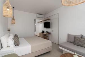 a white bedroom with a bed and a couch at Etherio Suites Milos in Pollonia