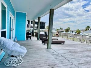 a porch of a blue house with benches on it at Dockside Dream Home for 10 in Galveston +35 photos