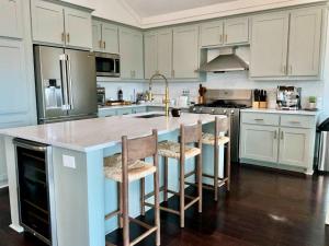 a kitchen with white cabinets and a island with bar stools at Dockside Dream Home for 10 in Galveston