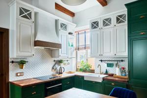 a green kitchen with white cabinets and a sink at Luxury OldTown Free Parking in Vilnius