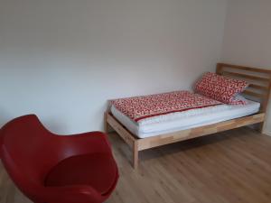 a bed and a red chair in a room at Traumwohnung in Feldrandlage in Rod am Berg