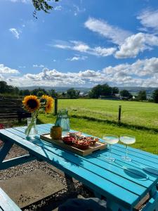 a blue picnic table with a plate of food and glasses at The Dome at Midauchengowan in Lochwinnoch
