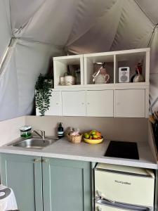 a kitchen with white cabinets and a sink in a tent at The Dome at Midauchengowan in Lochwinnoch