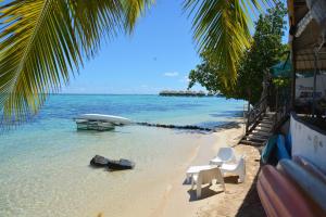a beach with two chairs and a table in the water at Fare Maheata in Pihaena