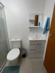 a white bathroom with a toilet and a sink at Cantinho da Lyah in Torres
