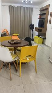 a living room with a table and yellow chairs at Cantinho da Lyah in Torres +7 photos