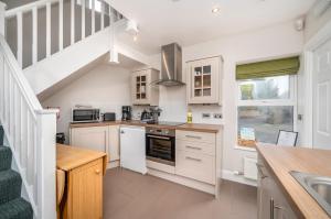 a kitchen with white cabinets and a staircase at Burnside, Dornoch in Dornoch +34 photos