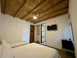 a bedroom with two beds and a tv and a window at Finca Campestre Colibrí in Quebradanegra