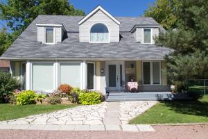 a white house with a gray roof at Gypsy by the Lake Bed and Breakfast in Sutton
