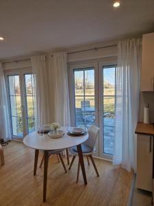 a white table and chairs in a room with windows at Ferienwohnung Weitblick Wiese in Neusitz