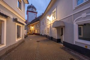 an empty street with a clock tower in the distance at COY Apartments Leoben - Central near Uni & Station with 24 7 Check-in in Leoben