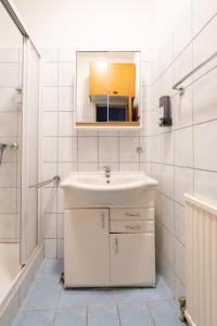 a white bathroom with a sink and a mirror at COY Apartments Leoben - Central near Uni & Station with 24 7 Check-in in Leoben +87 photos