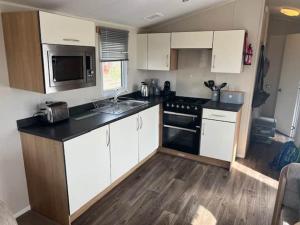 a kitchen with white cabinets and a black counter top at Devon Cliff Breaks in Exmouth