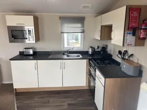a kitchen with white cabinets and a black counter top at Devon Cliff Breaks in Exmouth