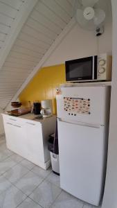 a kitchen with a microwave on top of a refrigerator at Chez Valé in Le Moule